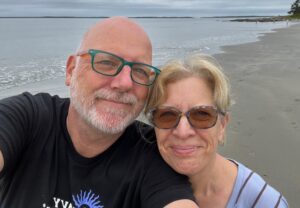 John and Heather smiling for the camera with a beach in the background