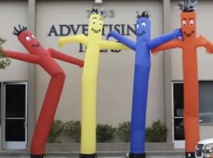 Four inflatable advertising stick figures standing in a row.